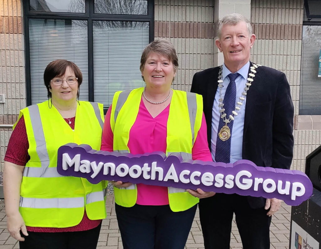 A group of people standing together with the Maynooth Access Group sign .